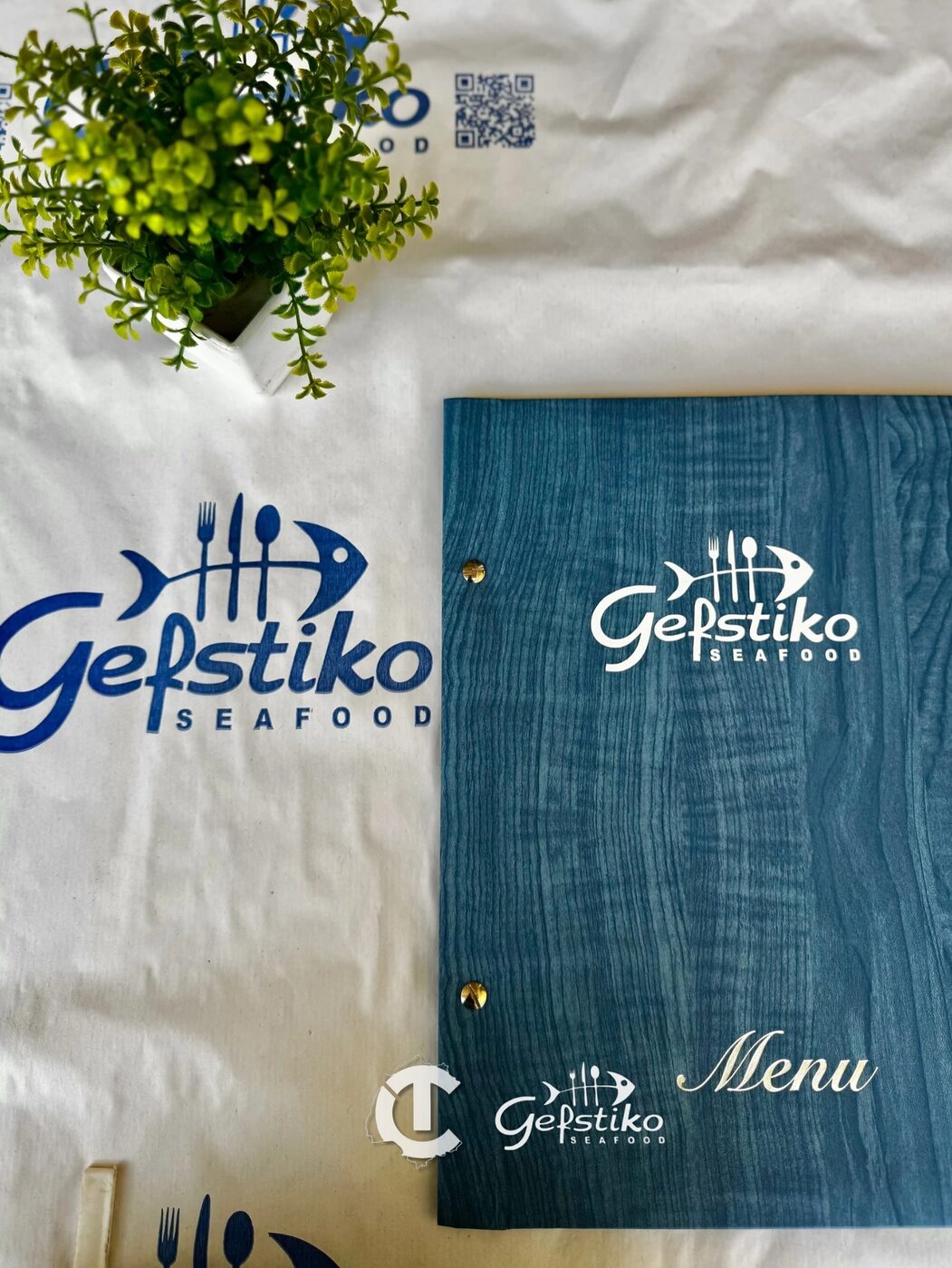 The Gefstiko menu and branding on a harbour-side table